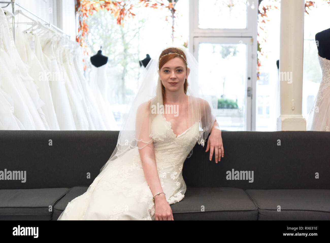 Una joven Chica pelo rojo retty trata sobre los vestidos de novia en una tienda nupcial. Ella está y sonriente Fotografía de stock - Alamy