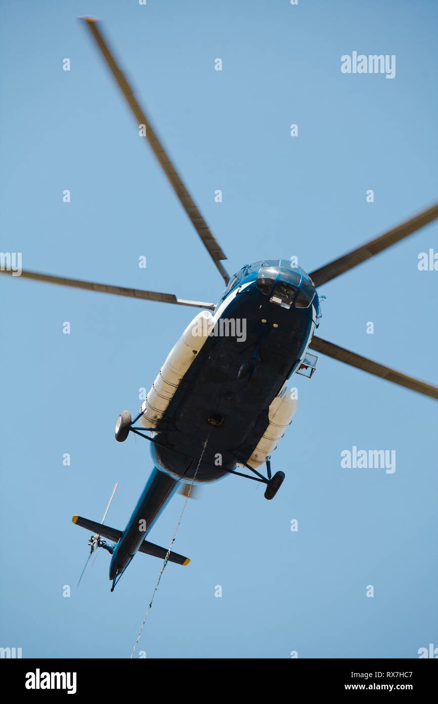 Carga de helicópteros pesados de mercancías con suspensión flotando en el cable. Cerrar hacia arriba desde la parte inferior. Foto de stock