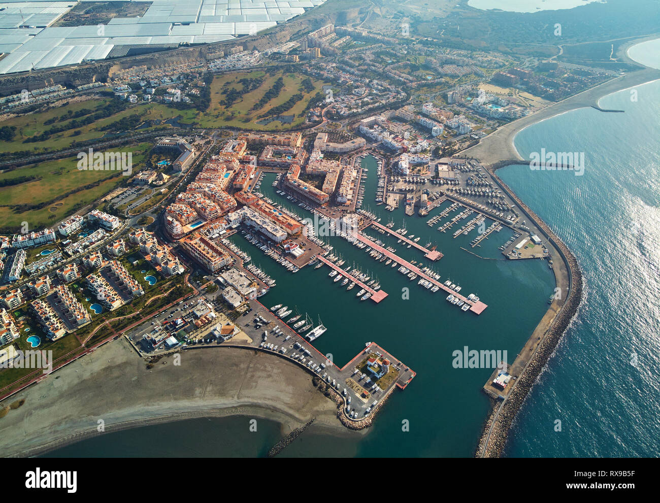 Vista aérea de punta de drone panorama de la ciudad de Almerimar, invernaderos, barcos náuticos amarrados en el puerto, playa de arena costera, España Foto de stock