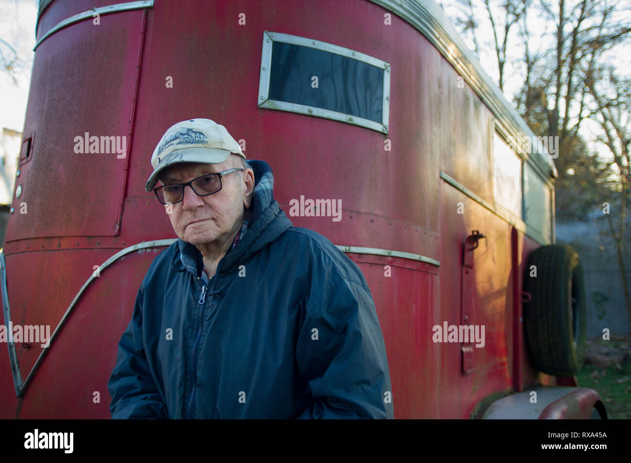 Retrato de altos hombre vestido con ropa de abrigo y la tapa estando en  contra de camper trailer en campo Fotografía de stock - Alamy