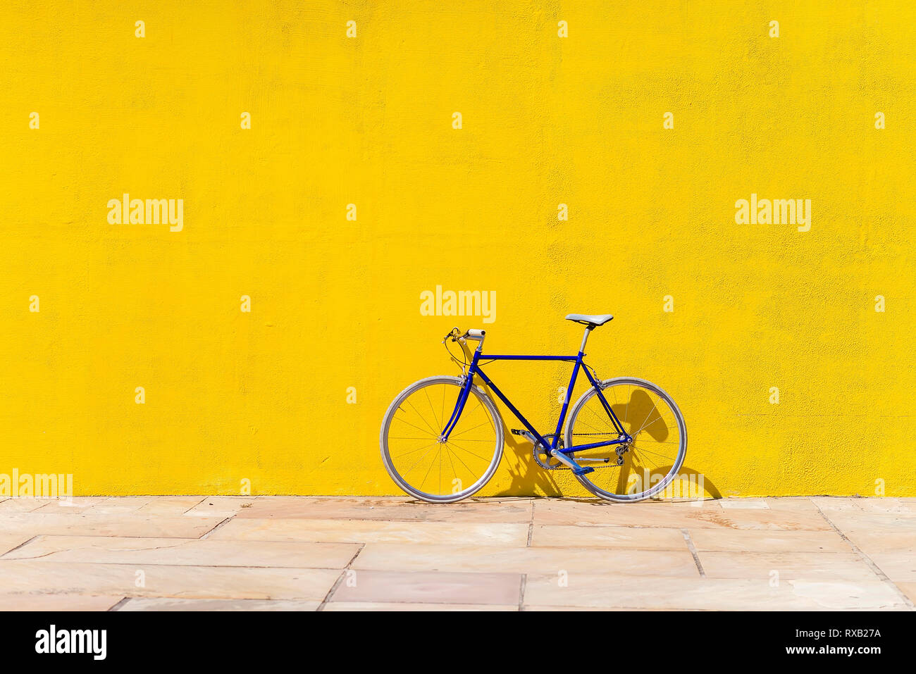 Bicicleta estacionada en la acera frente al muro durante día soleado Foto de stock