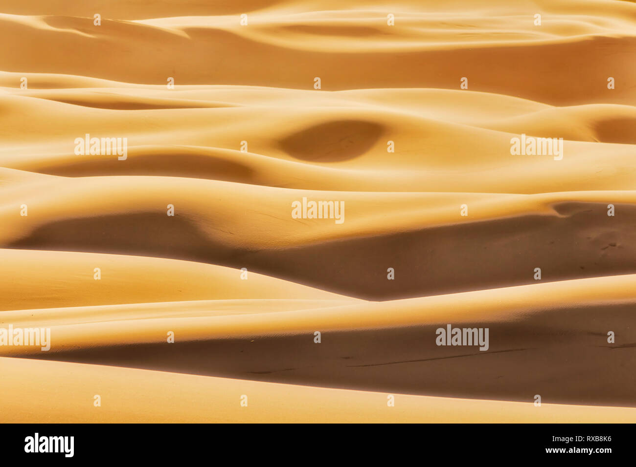 Formas simples formadas por la luz del sol y sombras sobre infinitas olas de dunas de arena en el árido desierto sin vida de Australian Pacific coast en Stockton Beach. Foto de stock