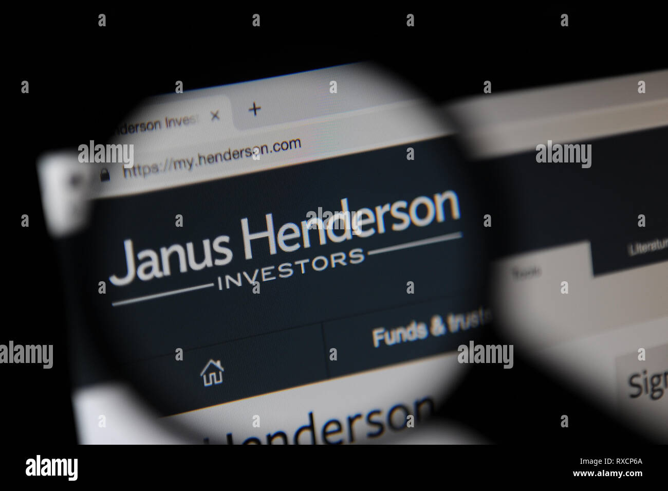 El Janus Henderson web es visto a través de una lupa. Janus Henderson se formó en 2017 cuando Janus Capital Group y Henderson Global Investor Foto de stock