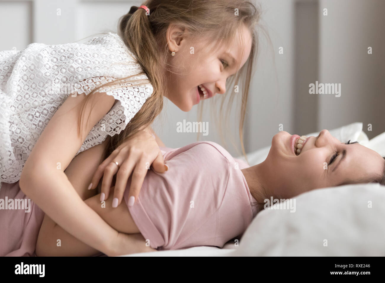 Niño feliz y madre divirtiéndose riendo jugando en la cama Foto de stock