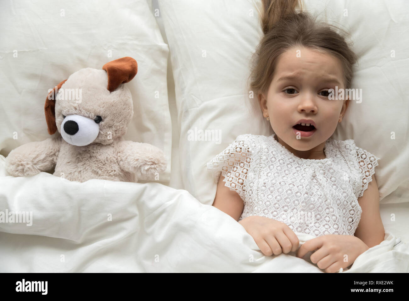 Asustado niño acostado en la cama con miedo de pesadilla de juguete Foto de stock