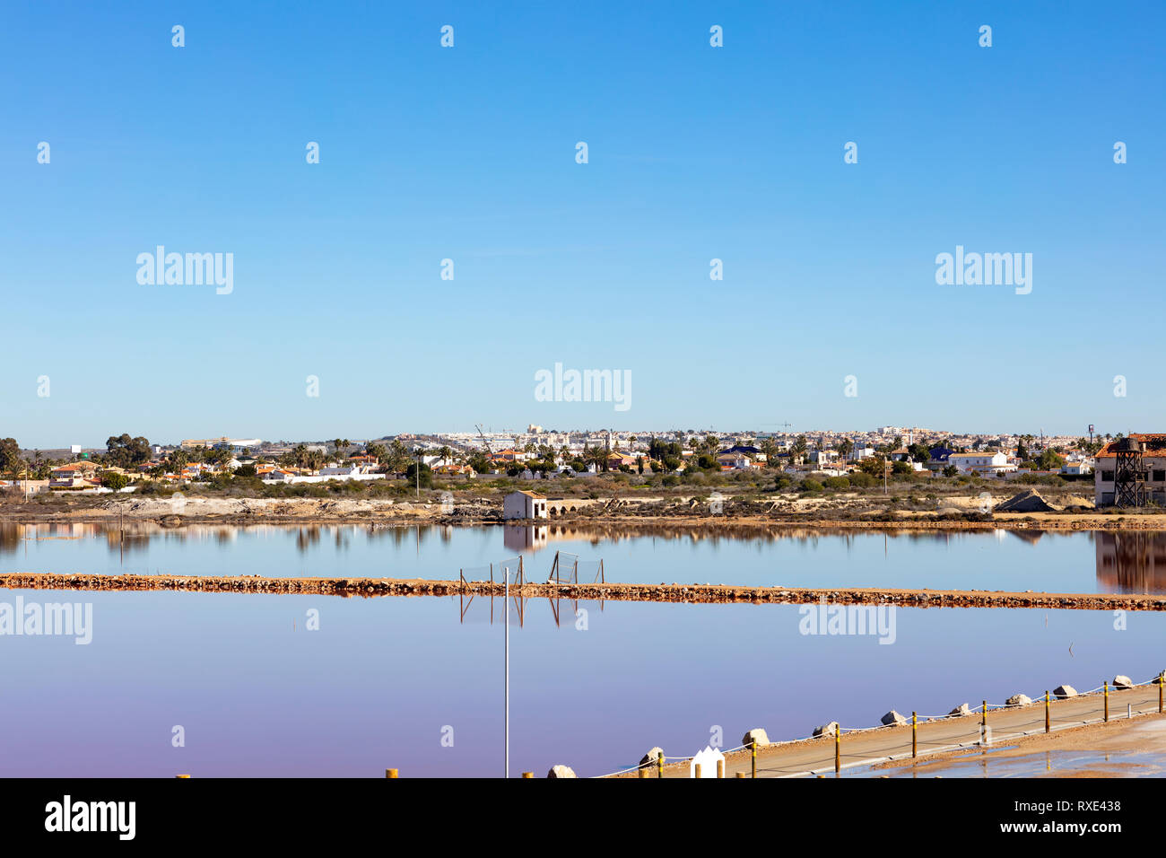 La orilla de un lago salino, como un espejo, con la ciudad de Torrevieja en el fondo Foto de stock