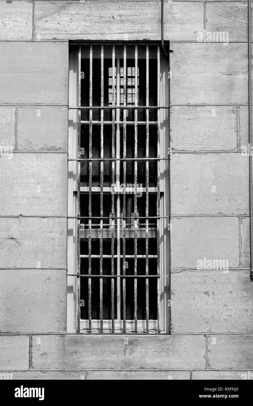 La pared de ladrillos de cemento con barras de acero a través de la ventana en una prisión Foto de stock