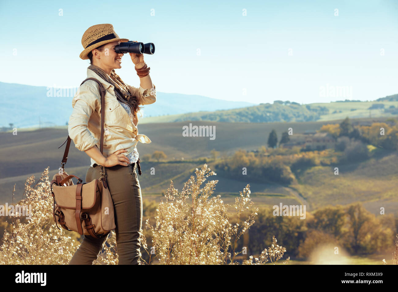 Mujer sonriente joven viajero en senderismo ropa con bolsa en la Toscana,  Italia mirando en la distancia a través de binoculares Fotografía de stock  - Alamy