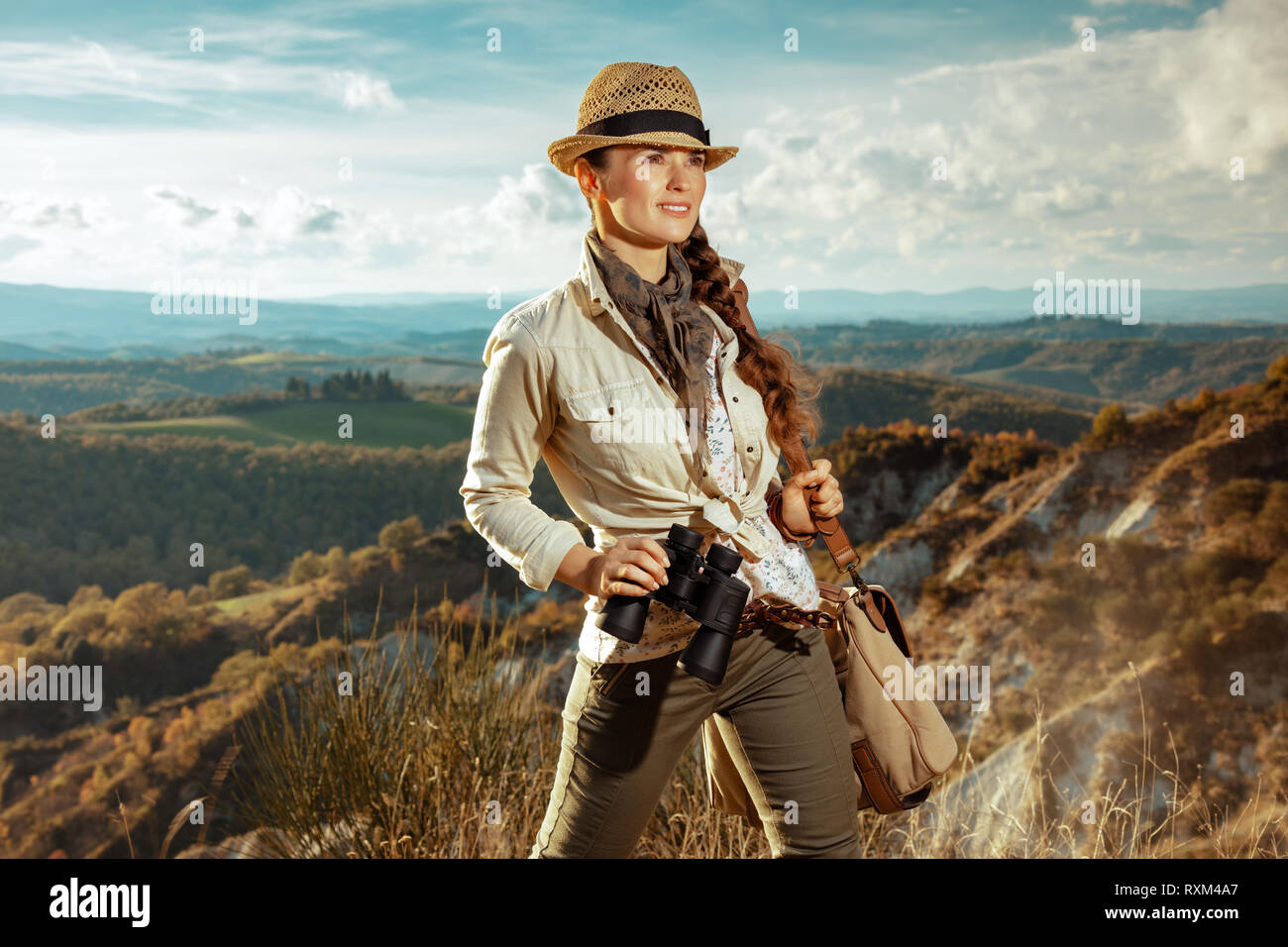 Viajero solitario aventura sonriente mujer en ropa de senderismo con bolsa  y prismáticos buscando en la distancia en la Toscana, Italia Fotografía de  stock - Alamy
