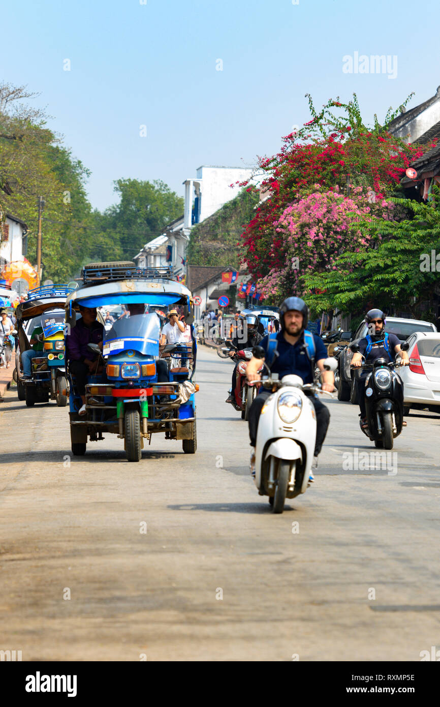 La vida diaria en las calles de Luang Prabang con el tráfico y los turistas que visitan la ciudad. Foto de stock