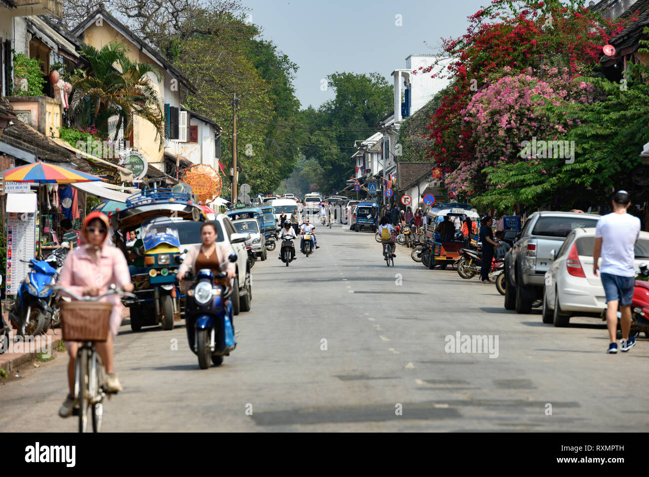 La vida diaria en las calles de Luang Prabang con el tráfico y los turistas que visitan la ciudad. Foto de stock