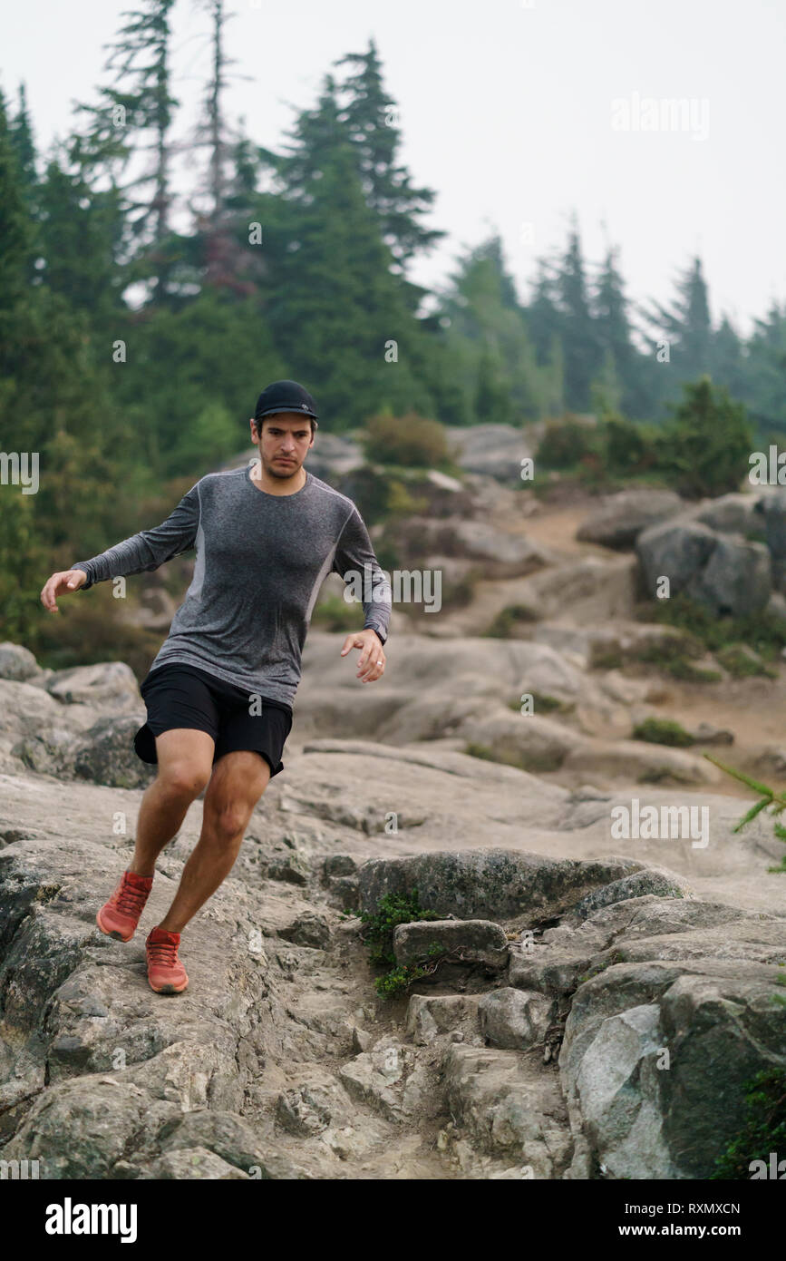 Un hombre joven trail runner corriendo a través del Parque Provincial de Cypress, British Columbia, Canadá Foto de stock