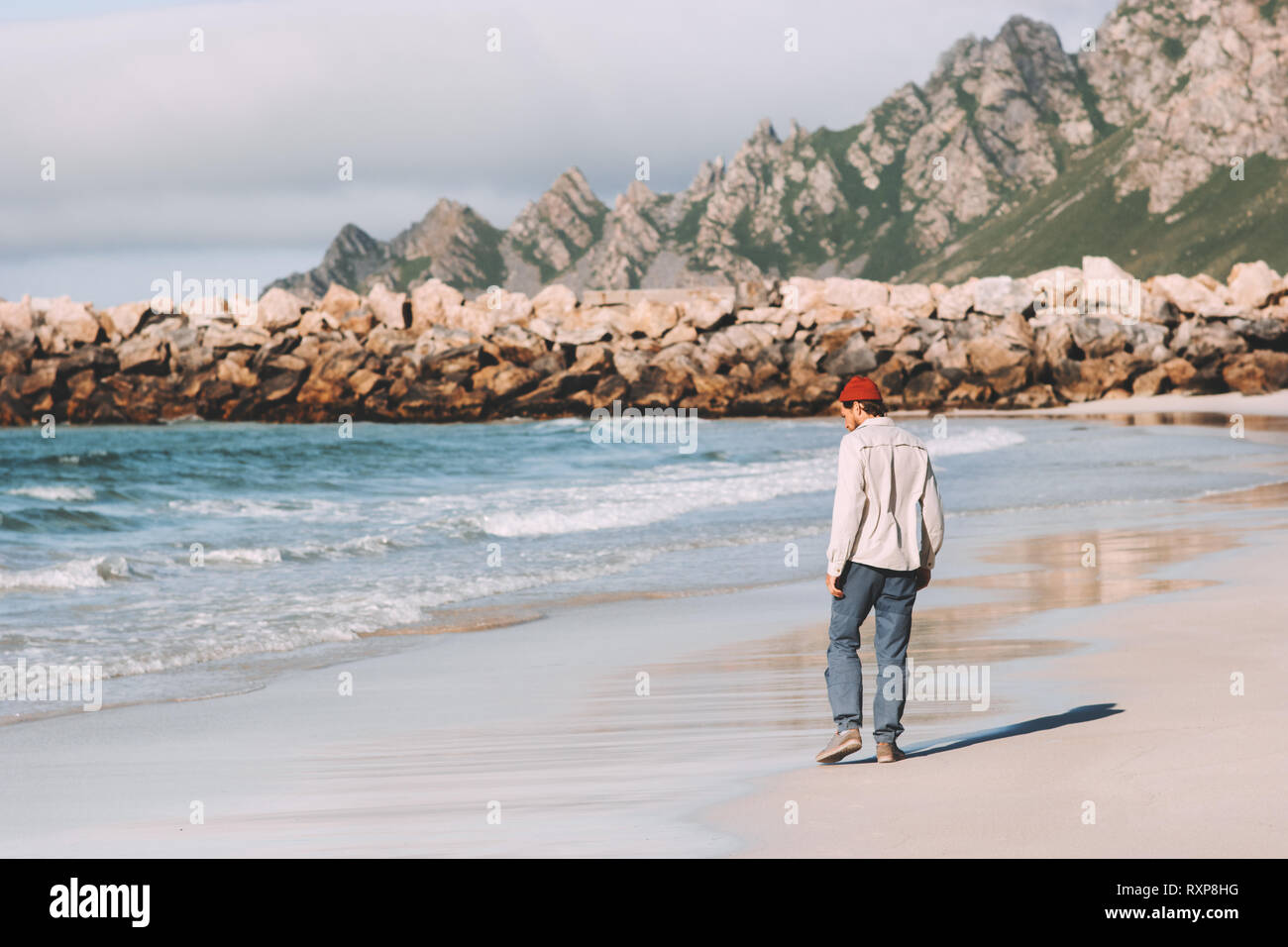 Hombre caminando solo en playa vacía viajando en Noruega de vacaciones activas en el estilo de vida al aire libre aventura viaje de fin de semana Foto de stock