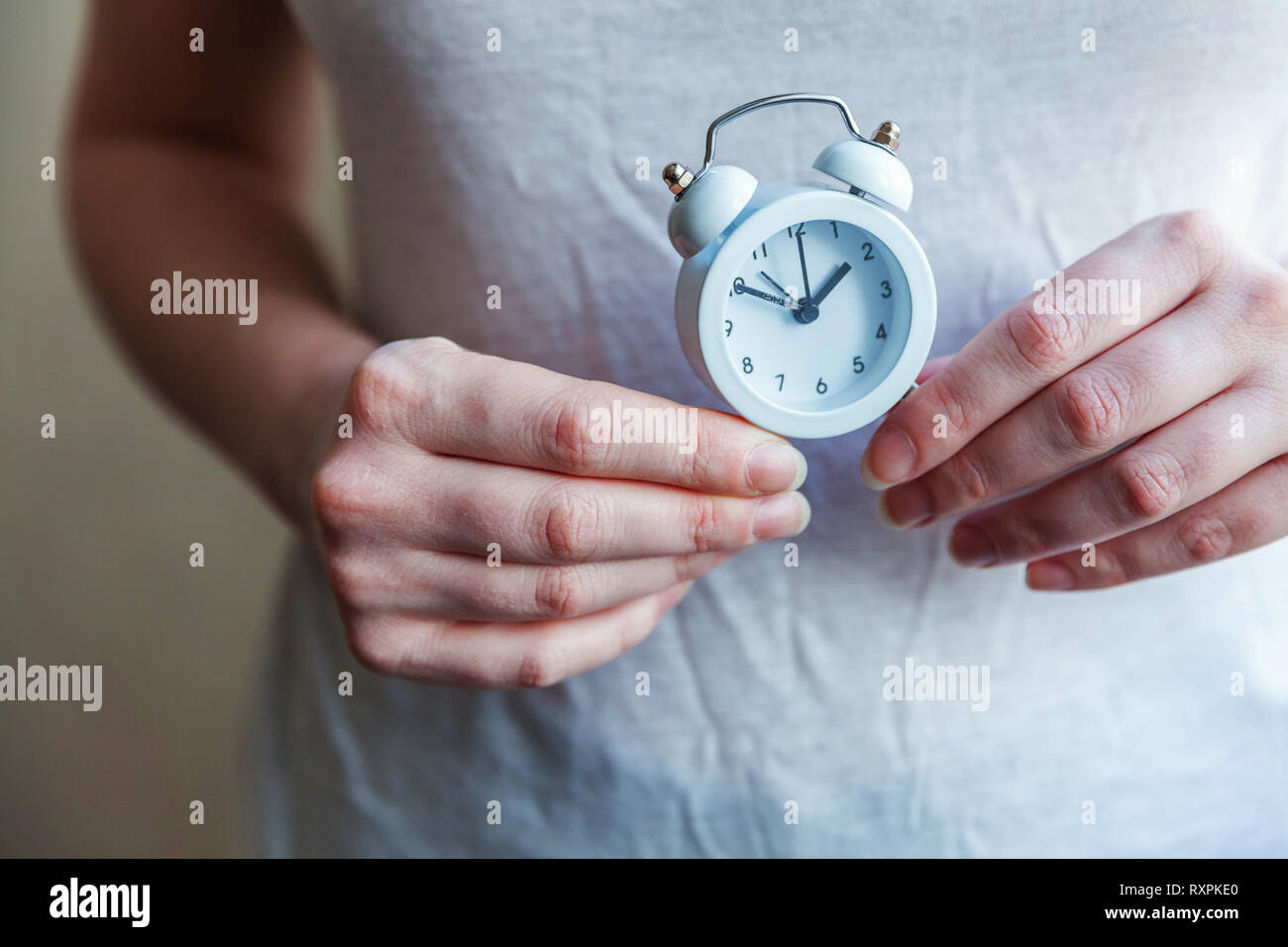 Mujer femenina manos sosteniendo sonando twin bell vintage clásico de despertador. El tiempo de descanso de la vida buenos días, noche despertarse despierto concepto Foto de stock