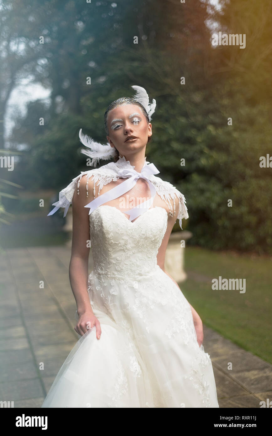 Una hermosa chica del Cáucaso en un vestido blanco plantea dramáticamente en un estilo gótico para una editorial photo shoot. El tema es de invierno Fotografía de stock -
