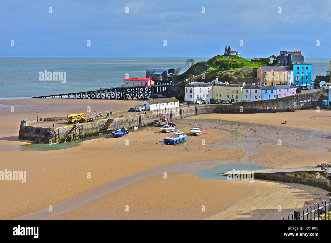 El bonito puerto en) Tenby, marea baja en invierno. Viejas y nuevas  estaciones de botes salvavidas con casas de color pastel con vistas a la  arenosa Playa Norte.S.Gales Fotografía de stock -