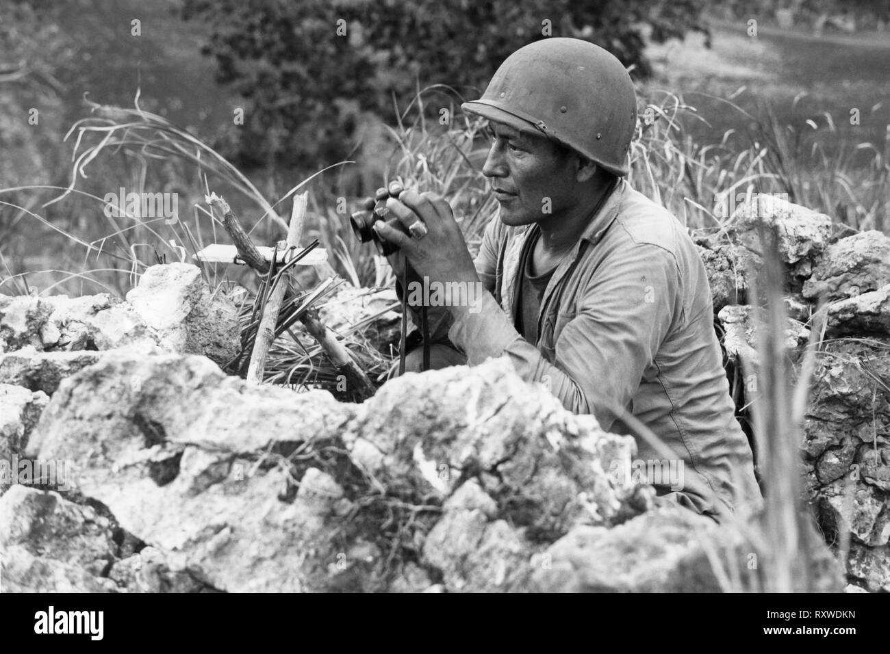 Código Navajo-lector Carl Gorman Pfc de Chinle, Arizona, que ocupaba un puesto de observación sobre una colina que domina la ciudad de Garapan, mientras que los Marines estadounidenses estaban consolidando sus posiciones en la isla de Saipán, Islas Marianas el 27 de junio de 1944, durante la batalla de Saipán. Foto de stock