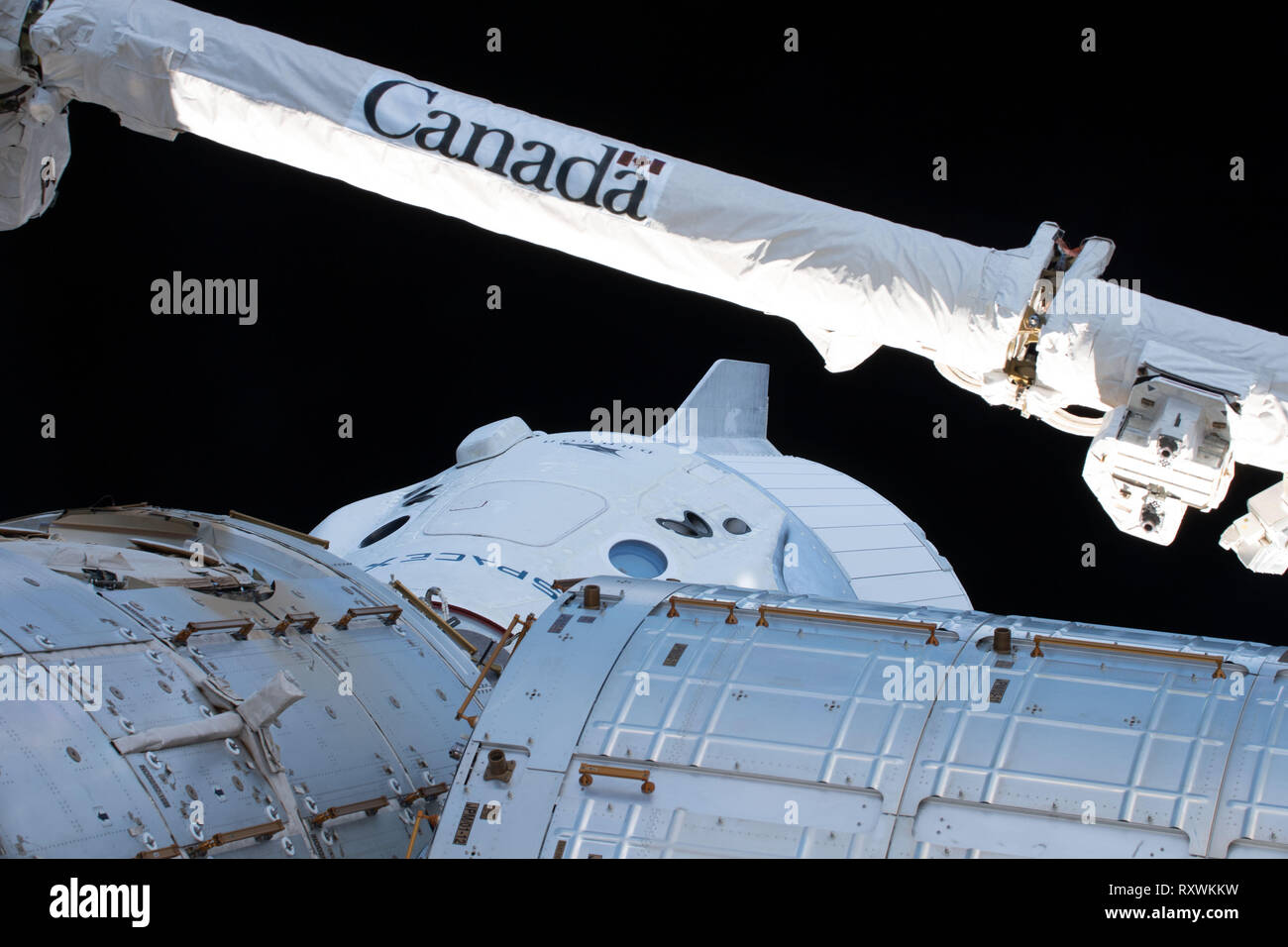 No Tripulado de la cápsula de la tripulación comercial Dragon SpaceX está acoplado con el módulo de armonía en la Estación Espacial Internacional el 4 de marzo de 2019 en la órbita de la tierra. La prueba de vuelo de las naves espaciales no tripuladas a la Estación Espacial Internacional es la primera prueba de la tripulación comercial y el comienzo de una nueva era para los viajes espaciales de la NASA. Foto de stock