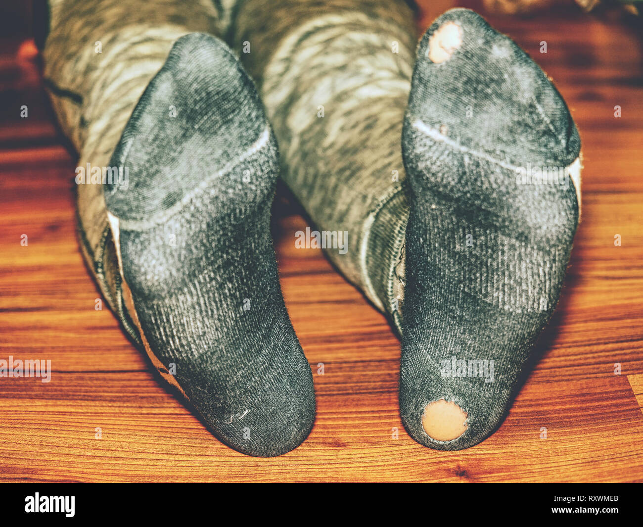 Calcetines con agujeros desgastados y los dedos de los pies que sobresalen  de ellos en el viejo piso de madera Fotografía de stock - Alamy