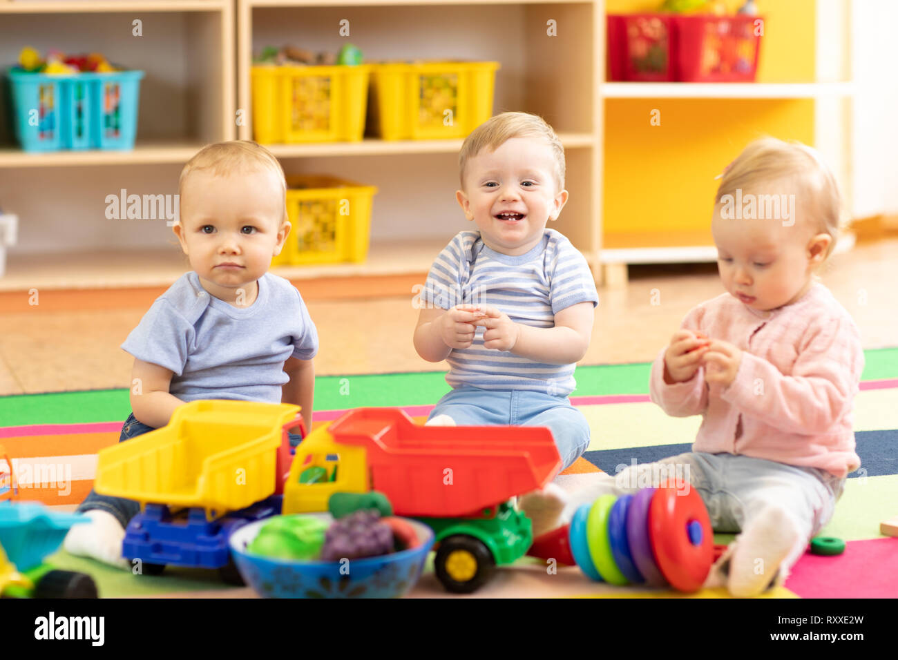 Guardería bebés niñas y niños jugando juntos en playroom en kindergarten  Fotografía de stock - Alamy