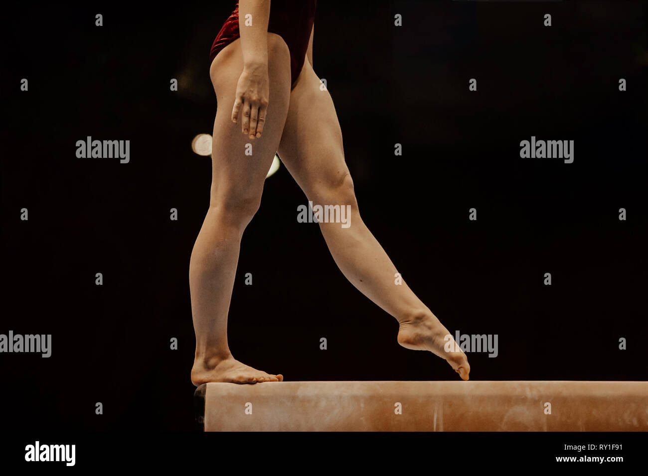 Vista lateral de la viga de equilibrio piernas gimnasta femenino competencia en gimnasia Foto de stock