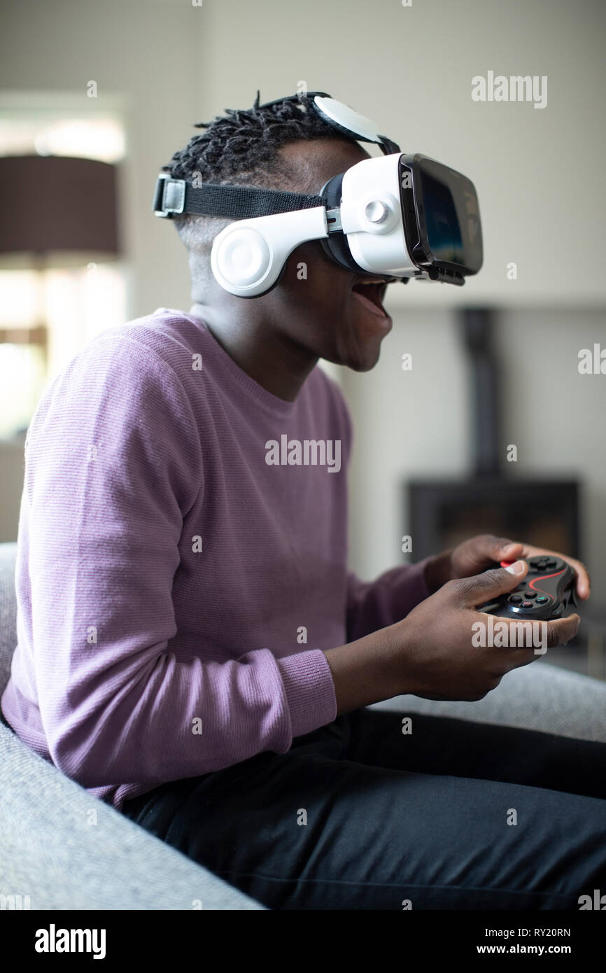 Emocionada Adolescente Jugar video juego en casa vistiendo casco de realidad virtual Foto de stock