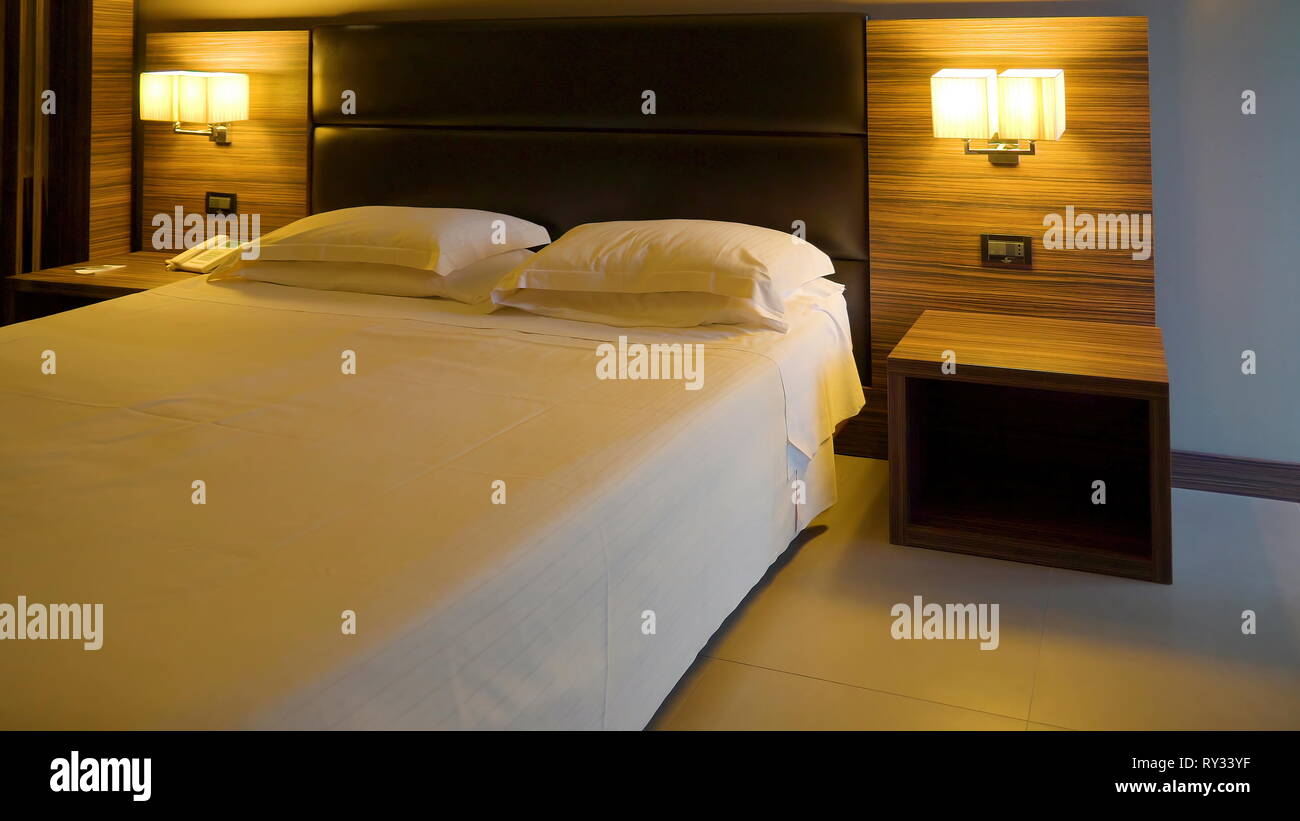 Una habitación de un hotel limpio con las luces de la lámpara en la cabecera  de la hoja limpia y blanca de la cama en Italia Fotografía de stock - Alamy