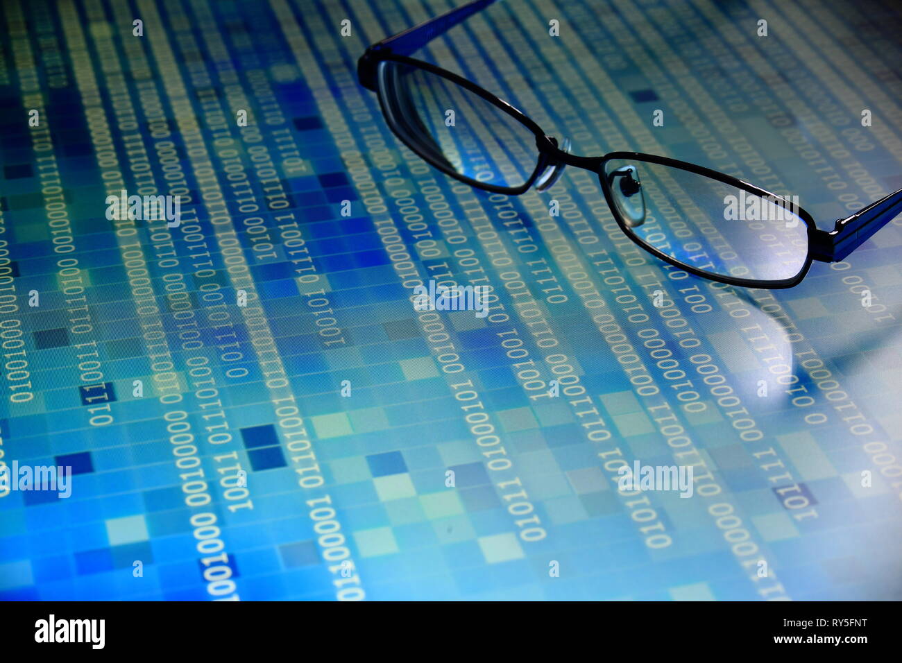 Análisis de grandes volúmenes de datos en código binario azul en el panel de led con fondo negro y vidrios colocados en el panel de información. hacker y análisis del código fuente. Foto de stock