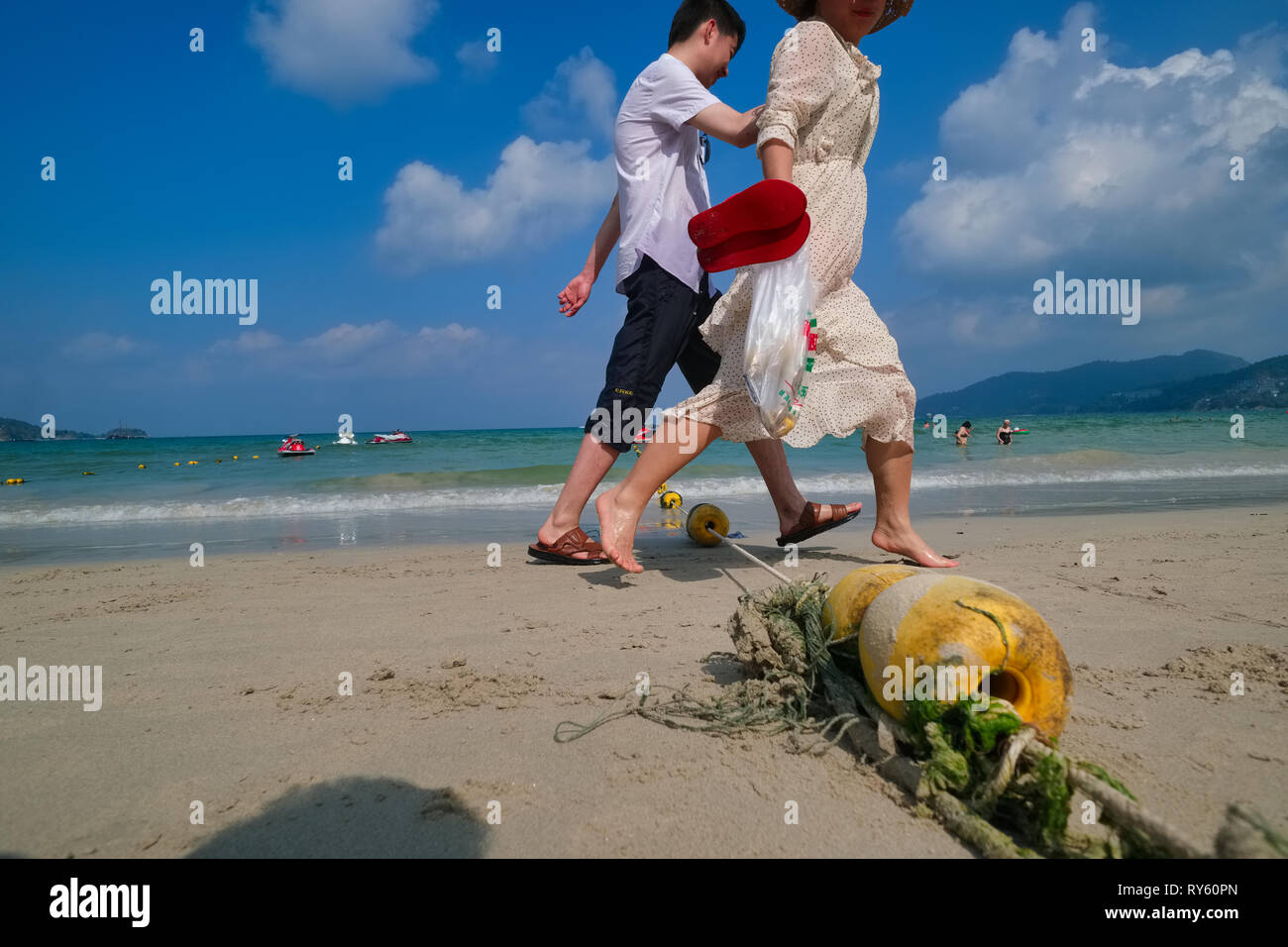 Los turistas en la playa de Patong, en Phuket, Tailandia, pisar sobre una línea de boyas utilizado para delimitar las áreas para nadar y para deportes acuáticos motorizados Foto de stock