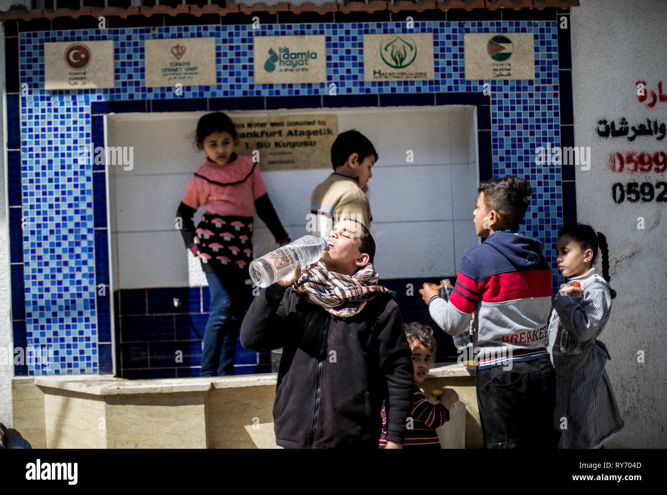 Los niños palestinos son vistos a acarrear agua en el campamento de refugiados de Bureij, en el sur de la Franja de Gaza. Más y más habitantes de Gaza están enfermando de su agua potable, destacando las cuestiones humanitarias hacia el enclave palestino que la ONU dice que podría volverse inhabitable en 2020. Foto de stock