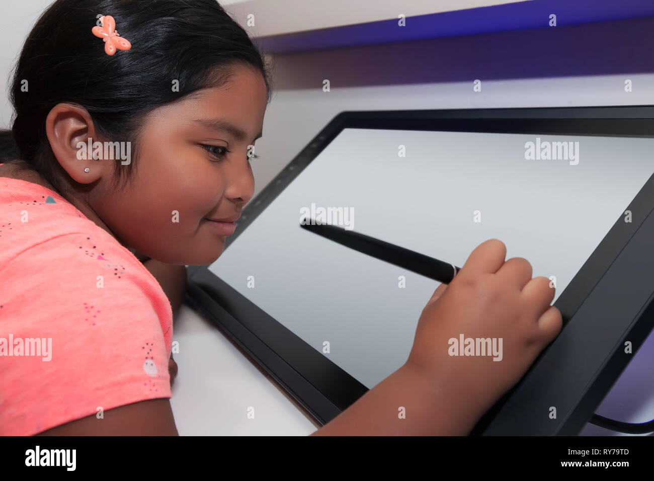 Estudiante de primaria sosteniendo un lápiz como lápiz y dibujo en una tableta de dibujo digital. Foto de stock