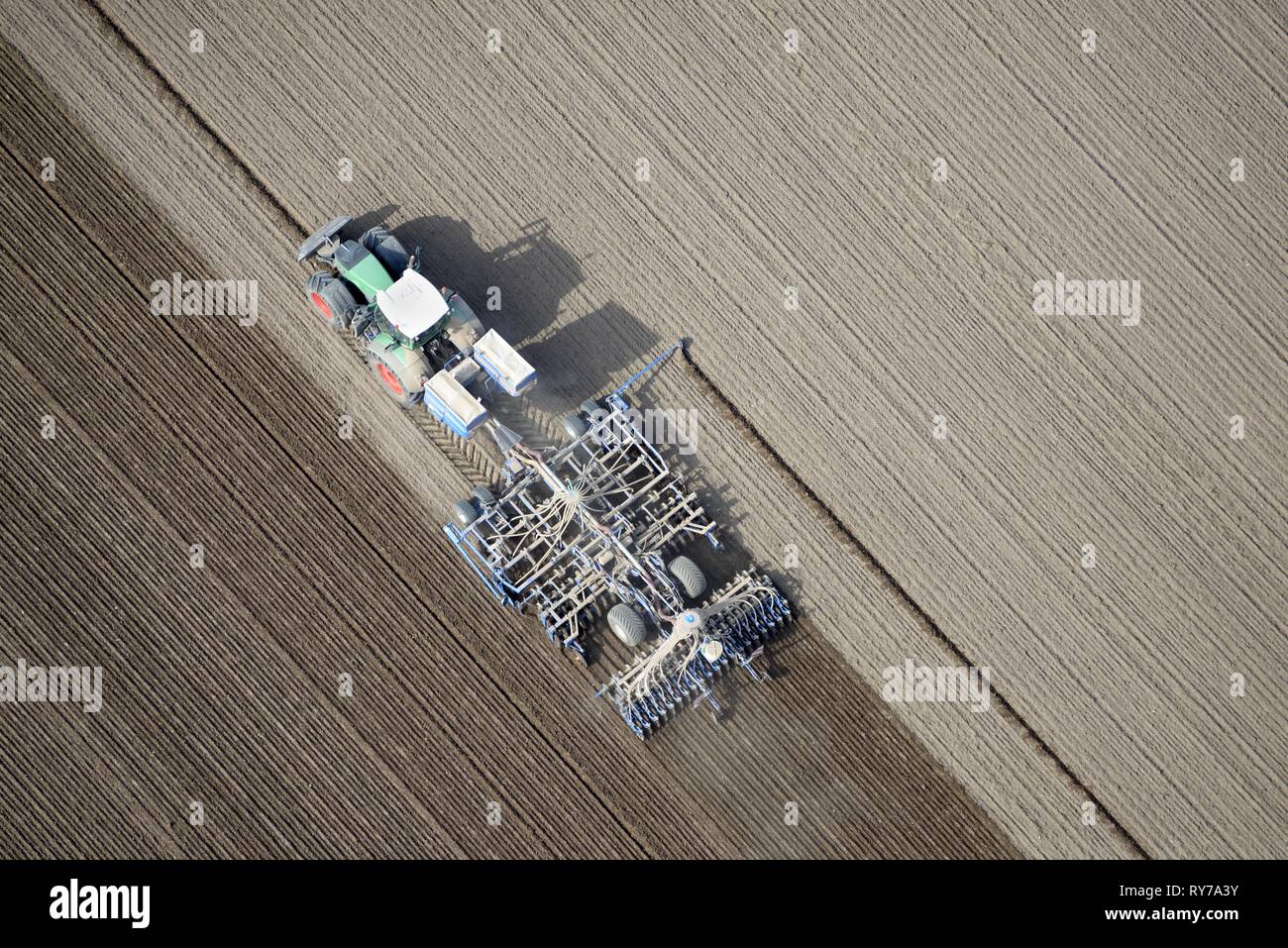 La agricultura moderna, el tractor trabajando la tierra cultivable en un campo, Schleswig-Holstein, Alemania Foto de stock