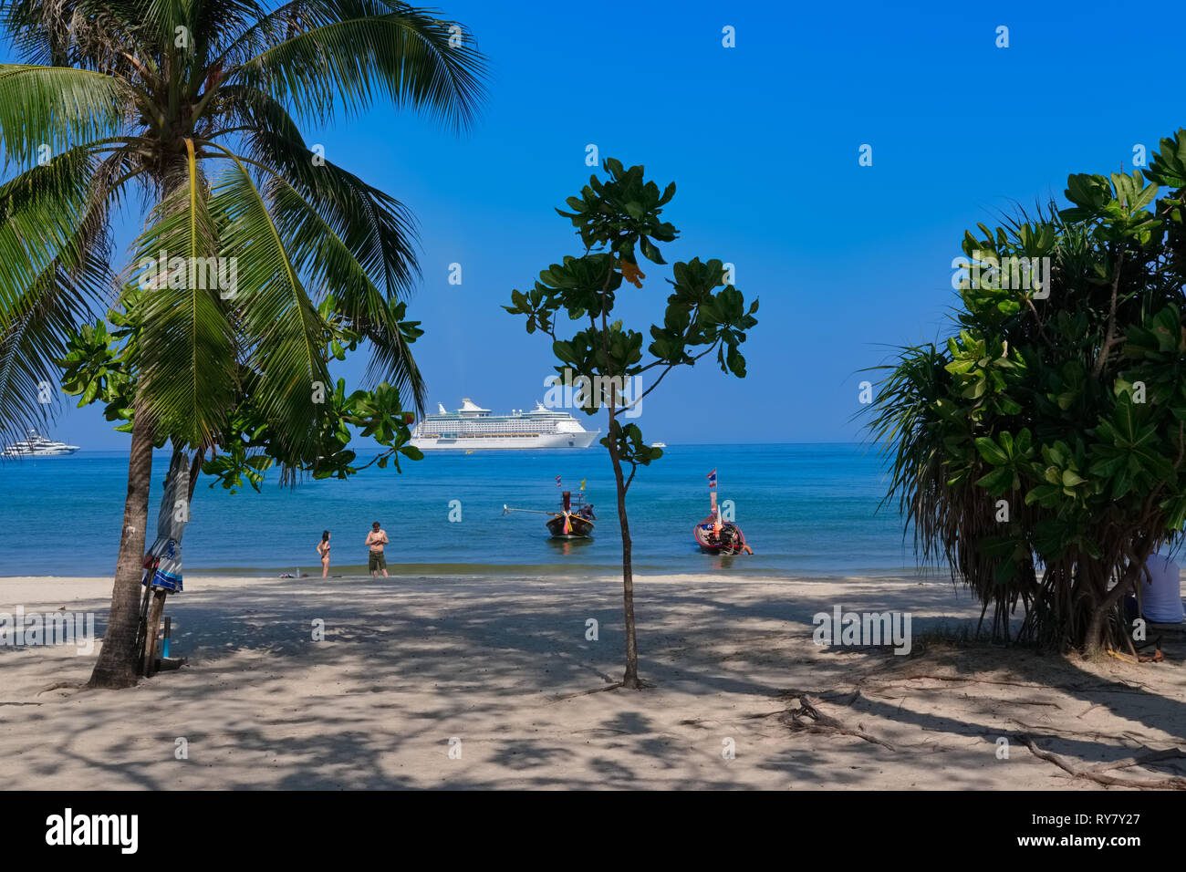 Los turistas de Patong Beach, Phuket, Tailandia, rodeado de vegetación, con un gran crucero anclado off shore Foto de stock