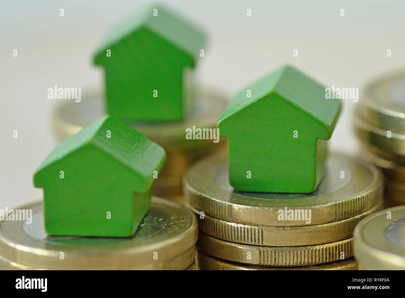 Casas en miniatura verde sobre pilas de moneda - Concepto de inversiones inmobiliarias, hipotecas, seguros de hogar y de préstamo, eco-friendly house Foto de stock