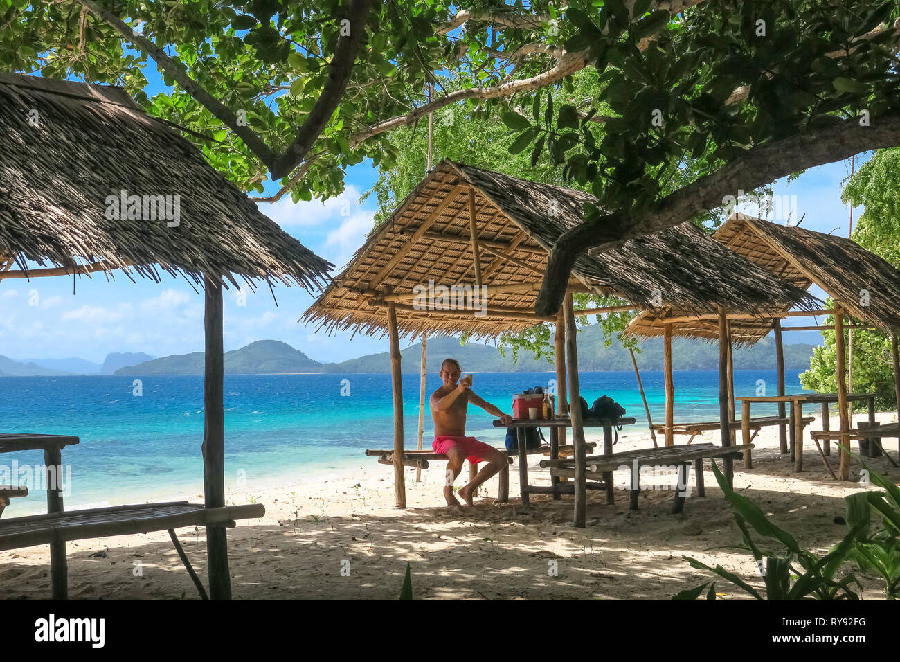 Turista holandesa Hombre bebiendo en Bamboo Beach hut Linapacan Isla Palawan - Filipinas Foto de stock
