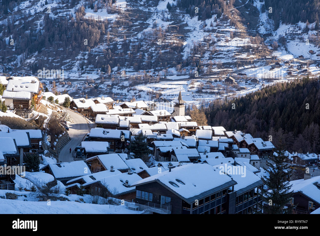 Ver abajo para Grimentz en la mañana, cuando el sol de invierno está llegando a la aldea. Vistas a la iglesia y los techos cubiertos de nieve. Cantón suizo de Valais Foto de stock