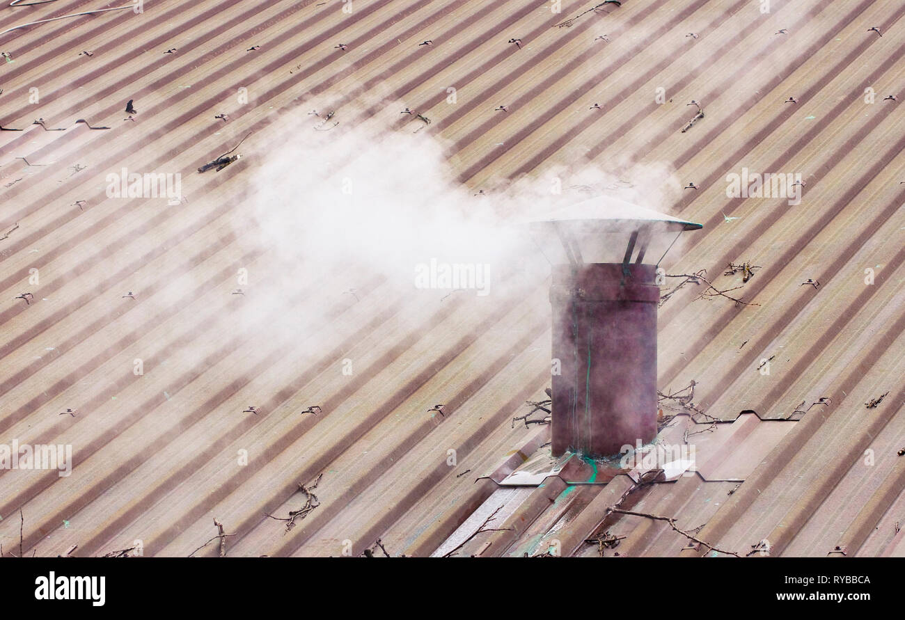 Chimenea de metal sobre el tejado de cobre con humo - imagen con espacio de copia Foto de stock