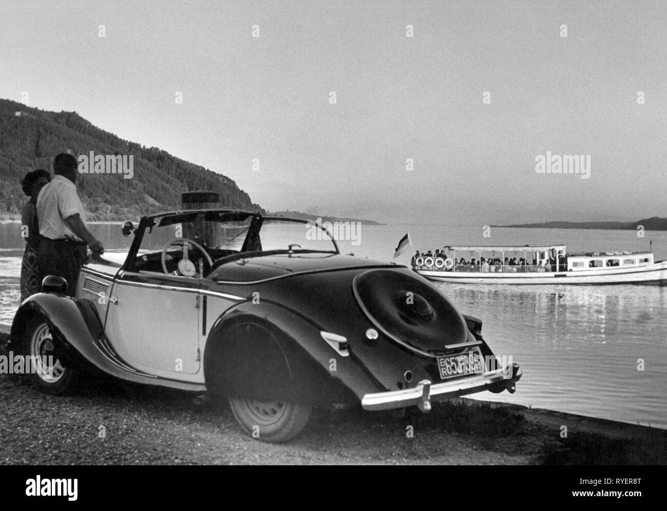 Transporte / Transporte, automóviles, variantes del vehículo, Ford Eifel Roadster 1938, vista desde detrás de la izquierda, en el lago de Constanza, en Alemania, en 1951, Paisaje, paisajes, lagos, lagunas, excursión en barco, barco de recreo, barcos de excursiones, embarcaciones de recreo, viaje, viaje, viaje, viaje, viaje, vacaciones, vacaciones, tiempo de ocio, tiempo libre, tiempo libre, deportivo, descapotable, coches deportivos, roadsters, dos puertas, dos puertas, motor car, auto, automóvil, coche, automóvil de pasajeros, automóviles, autos, automóviles, coches de pasajeros, vehículos, vehículos, Oeste, Ge-Clearance-Info-Not-Available Additional-Rights Foto de stock