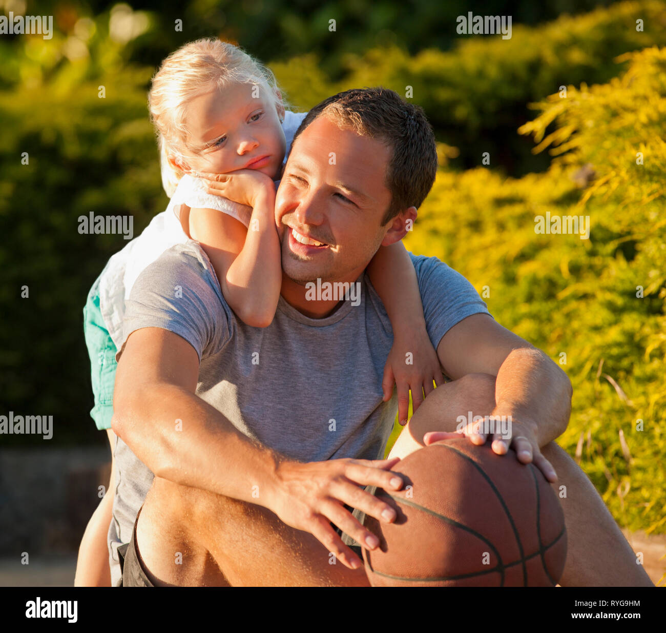 Padre sonriente sentado en un camino con su hija. Foto de stock