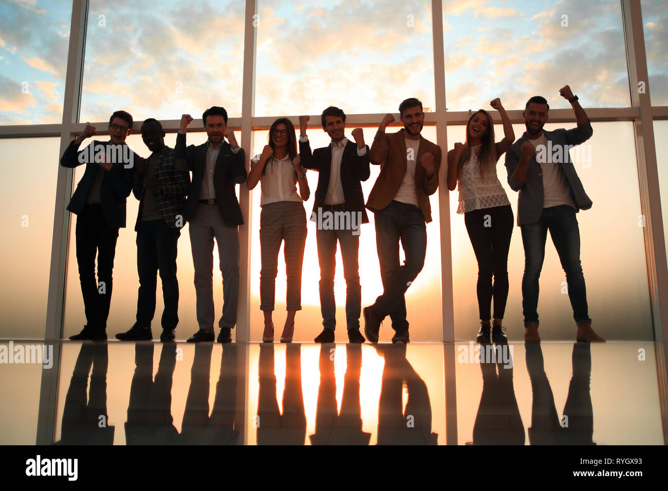 Grupo de jóvenes profesionales de pie en una oficina con una ventana grande Foto de stock