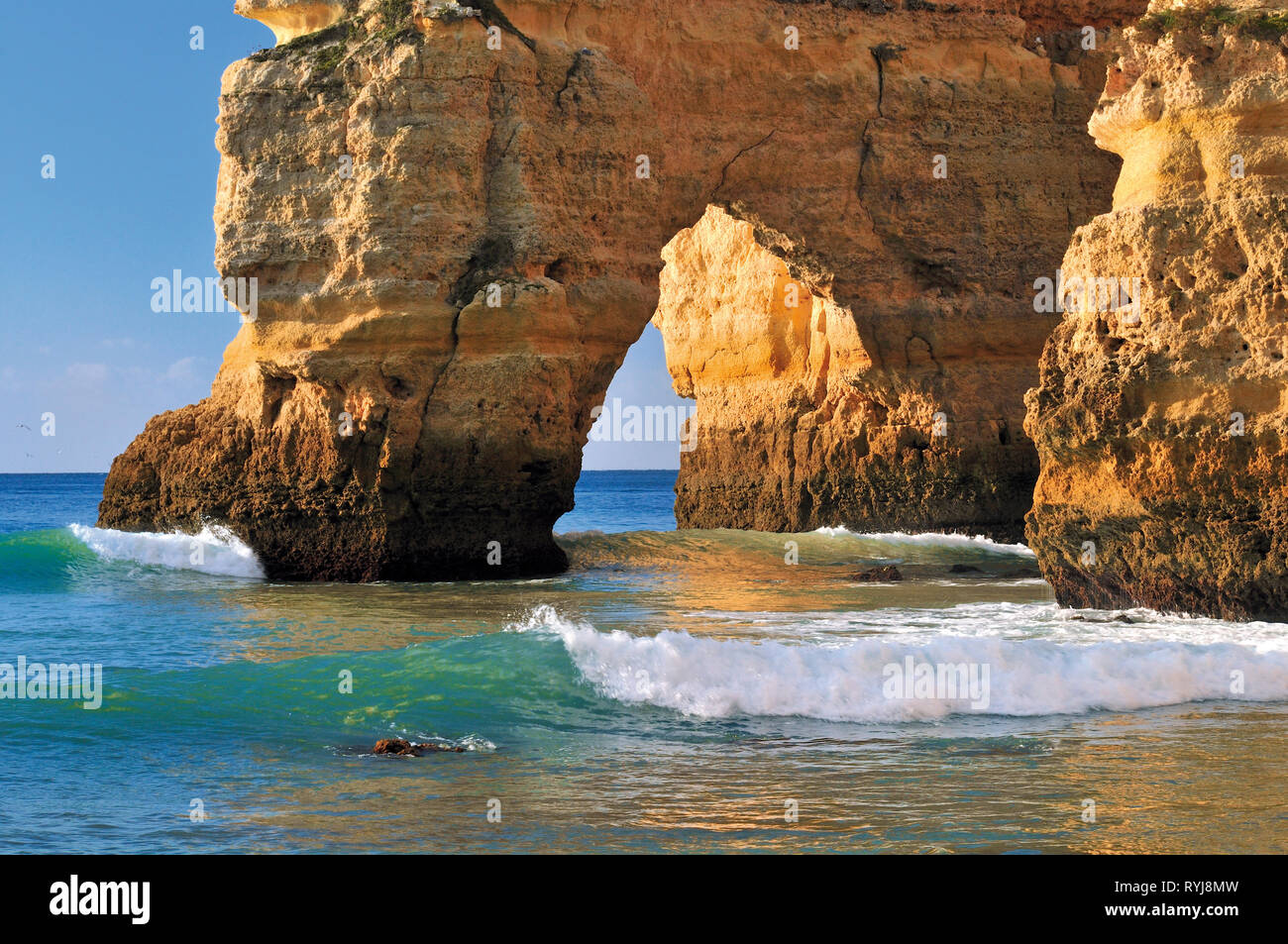 Con arco de roca caliza y suaves olas de agua turquesa en día soleado Foto de stock