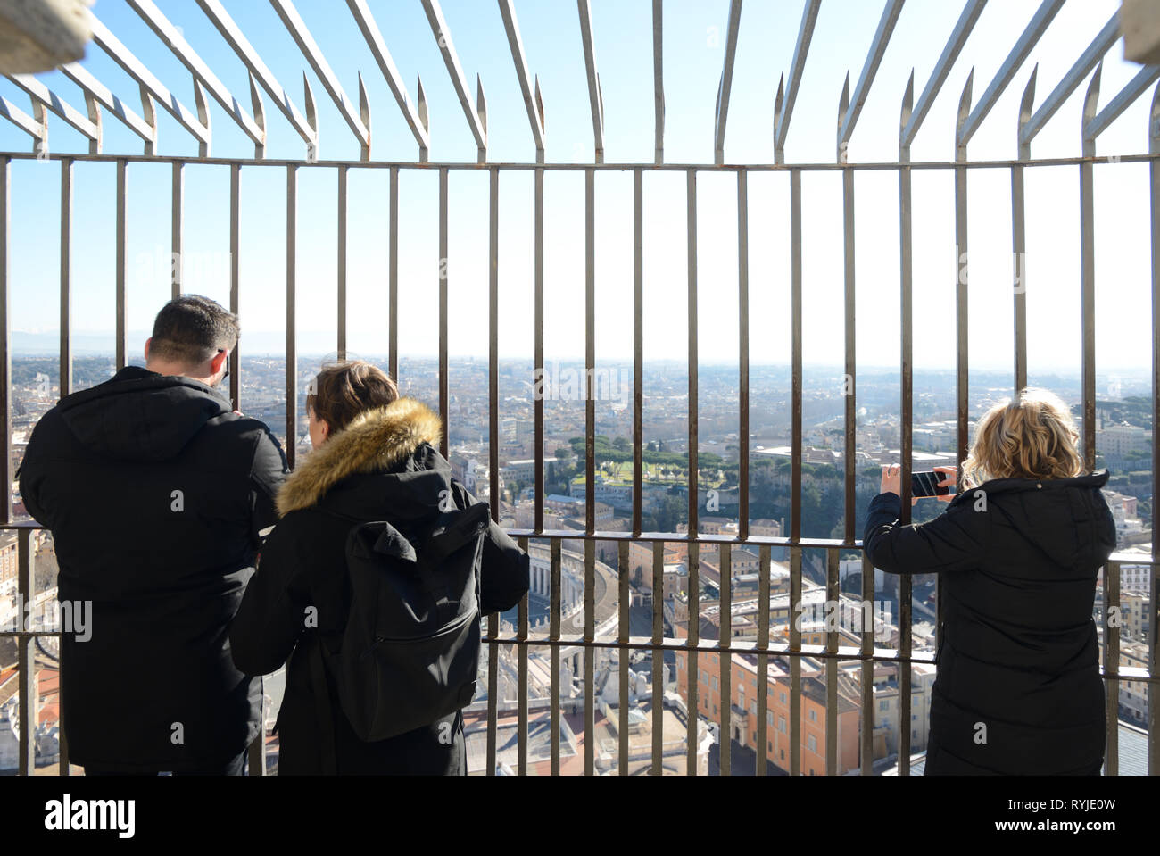 Tres turistas admirando la vista desde la cima de San Peters Basilca cúpula sobre Roma Italia Foto de stock