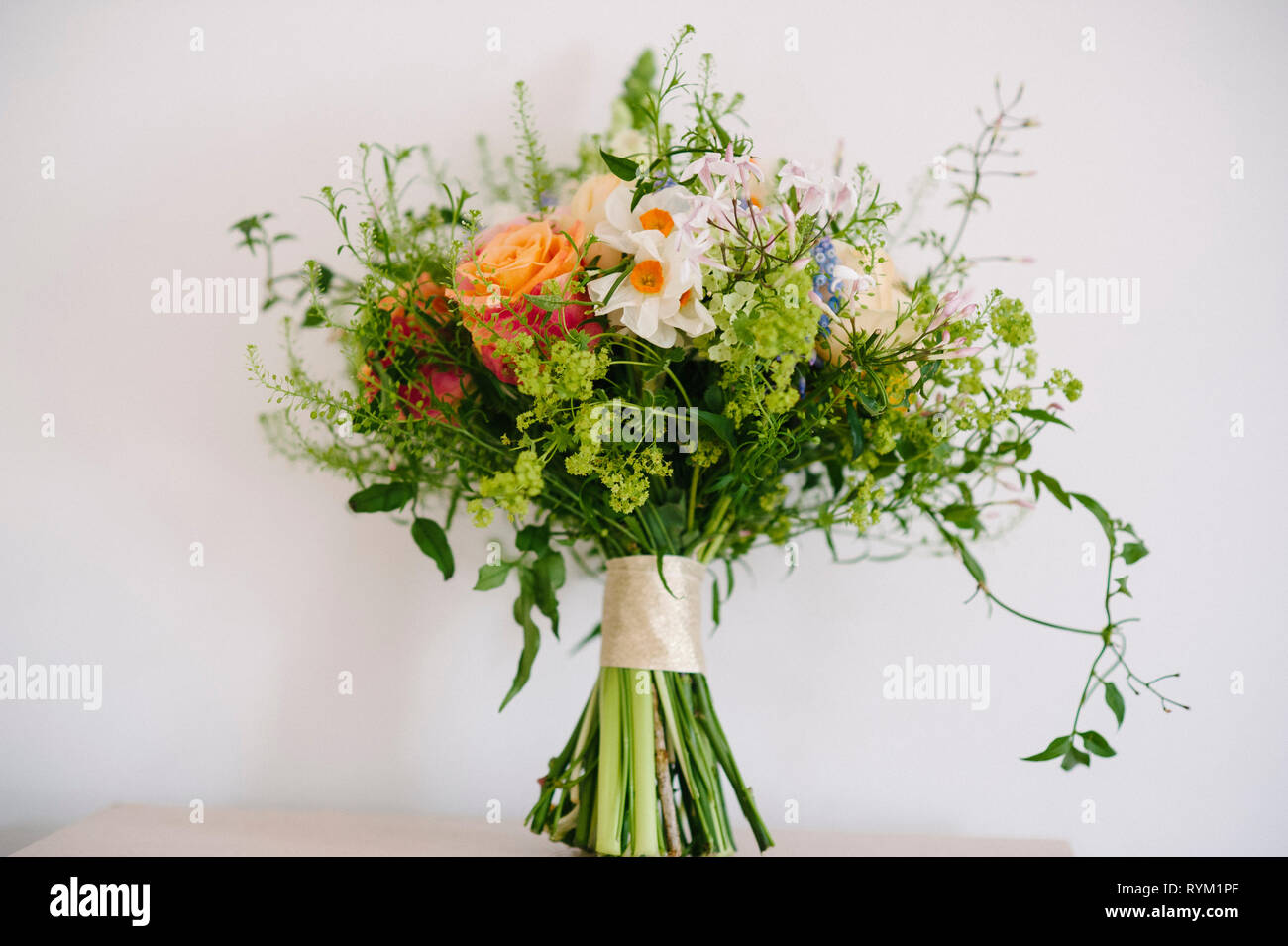 Un bonito ramo de flores de boda rústico con colores pastel sobre un fondo liso Foto de stock