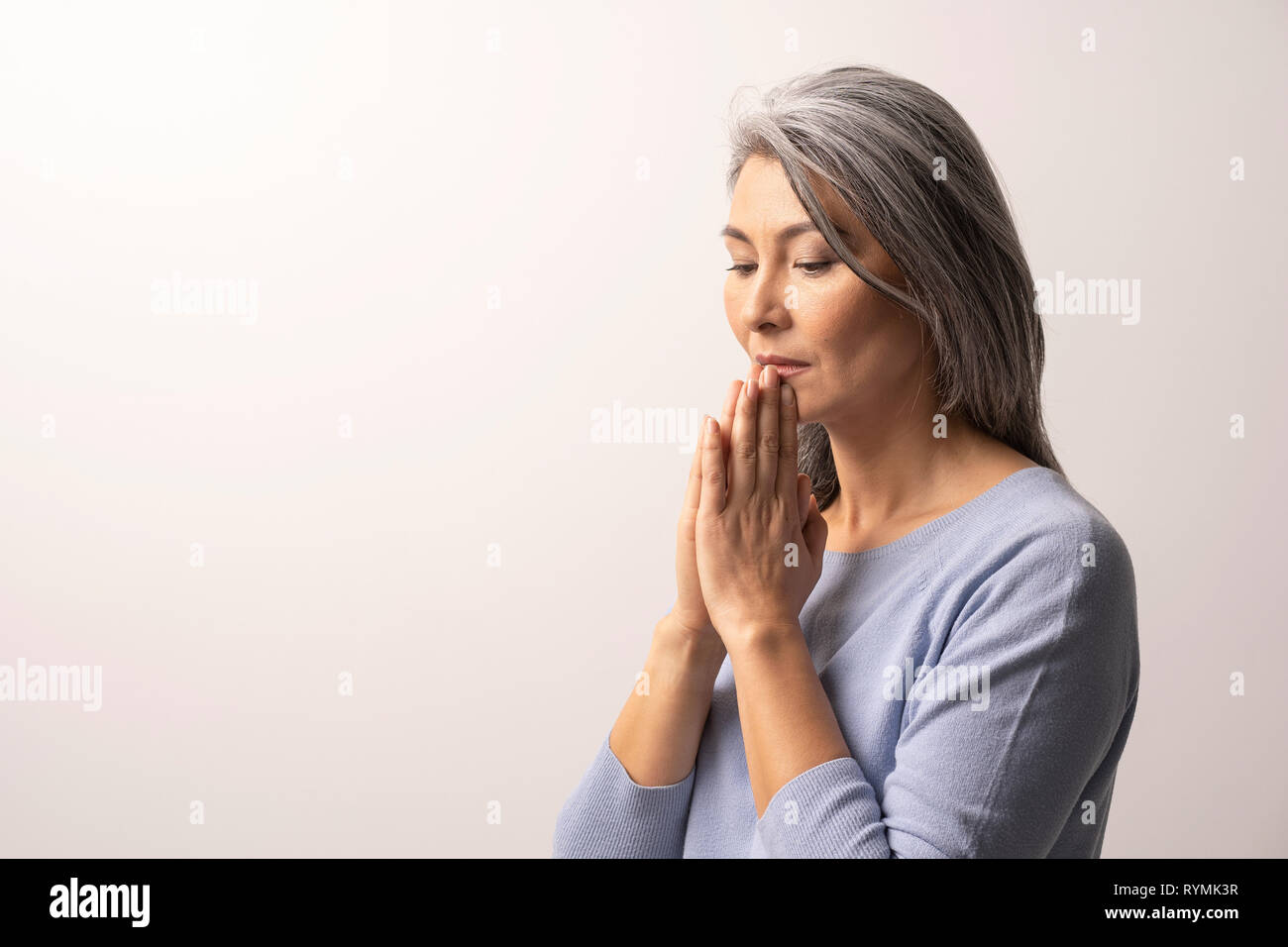 Mujer Asiática maduros orando sobre fondo blanco. Foto de stock