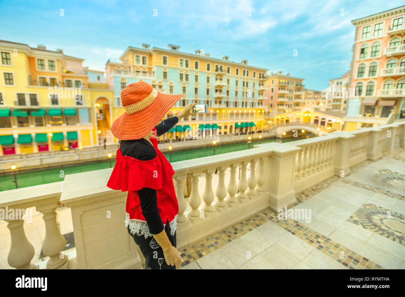 Turismo en Oriente Medio. Mujer toma la foto con el smartphone de Venecia, Doha, Qatar, en la hora azul. Vista aérea del famoso puente de Qanat Quartier Foto de stock