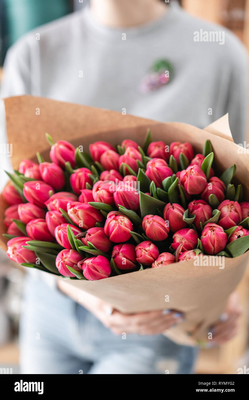 Hermosa joven mujer sosteniendo una primavera Ramo de tulipanes rojos en su  mano. Ramo de flores de primavera frescos cortados en manos femeninas  Fotografía de stock - Alamy