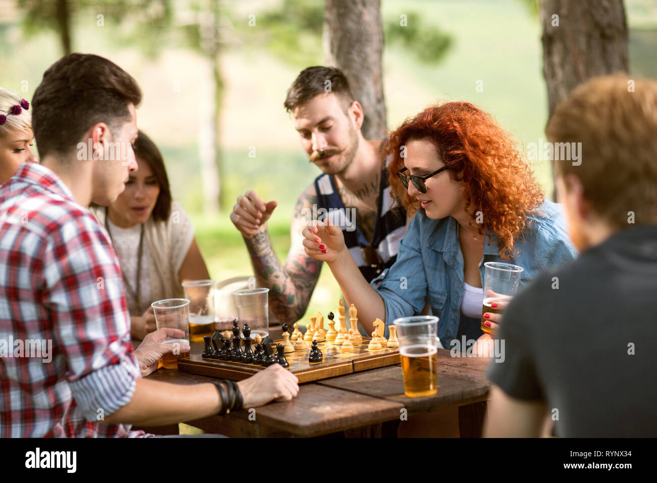 Un grupo de amigos, jugar ajedrez y bebe cerveza en un campamento de verano  en el bosque Fotografía de stock - Alamy