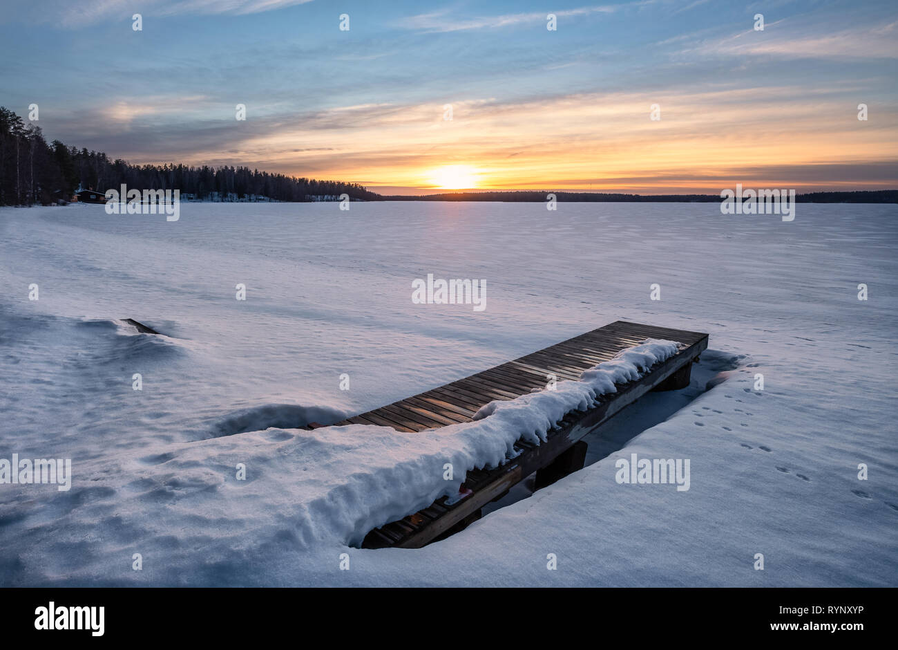 Pintoresco paisaje invernal con Pier y el atardecer en luz del atardecer en Finlandia Foto de stock