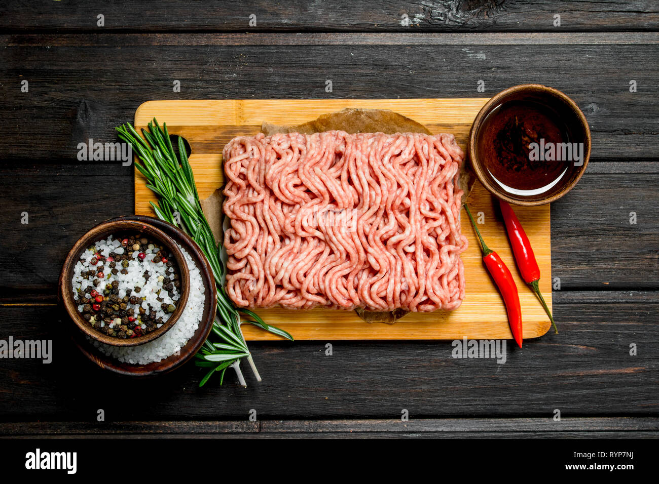 Carne picada y preparados de carne cruda con especias y hierbas . Sobre un fondo de madera. Foto de stock