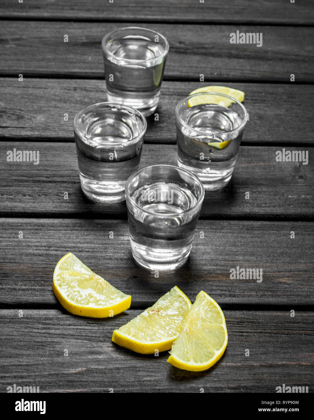 El vodka en un vaso de cristal y rodajas de limón. Sobre fondo de madera  Fotografía de stock - Alamy